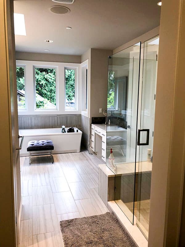 Spacious bathroom with freestanding tub, vanity, and glass-enclosed shower. Large windows offer natural light.