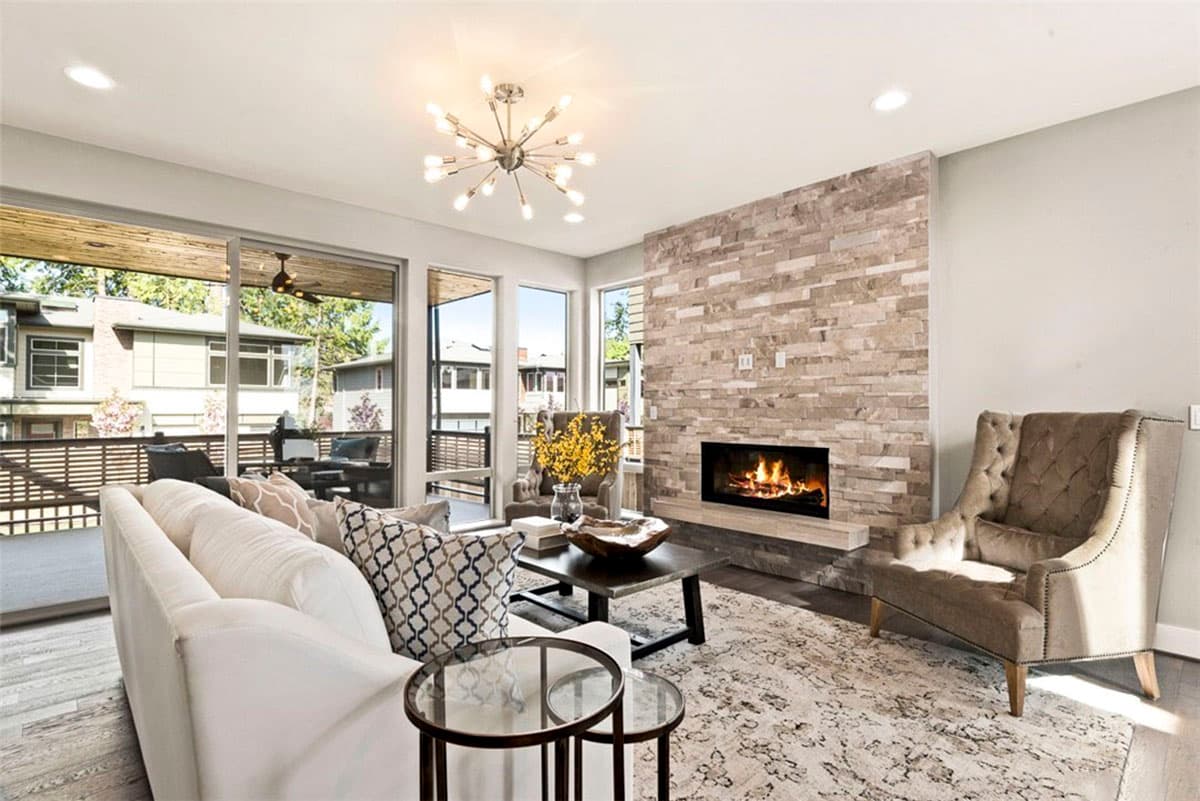 Living room with stone fireplace, large windows, and sliding glass doors opening to a covered patio.