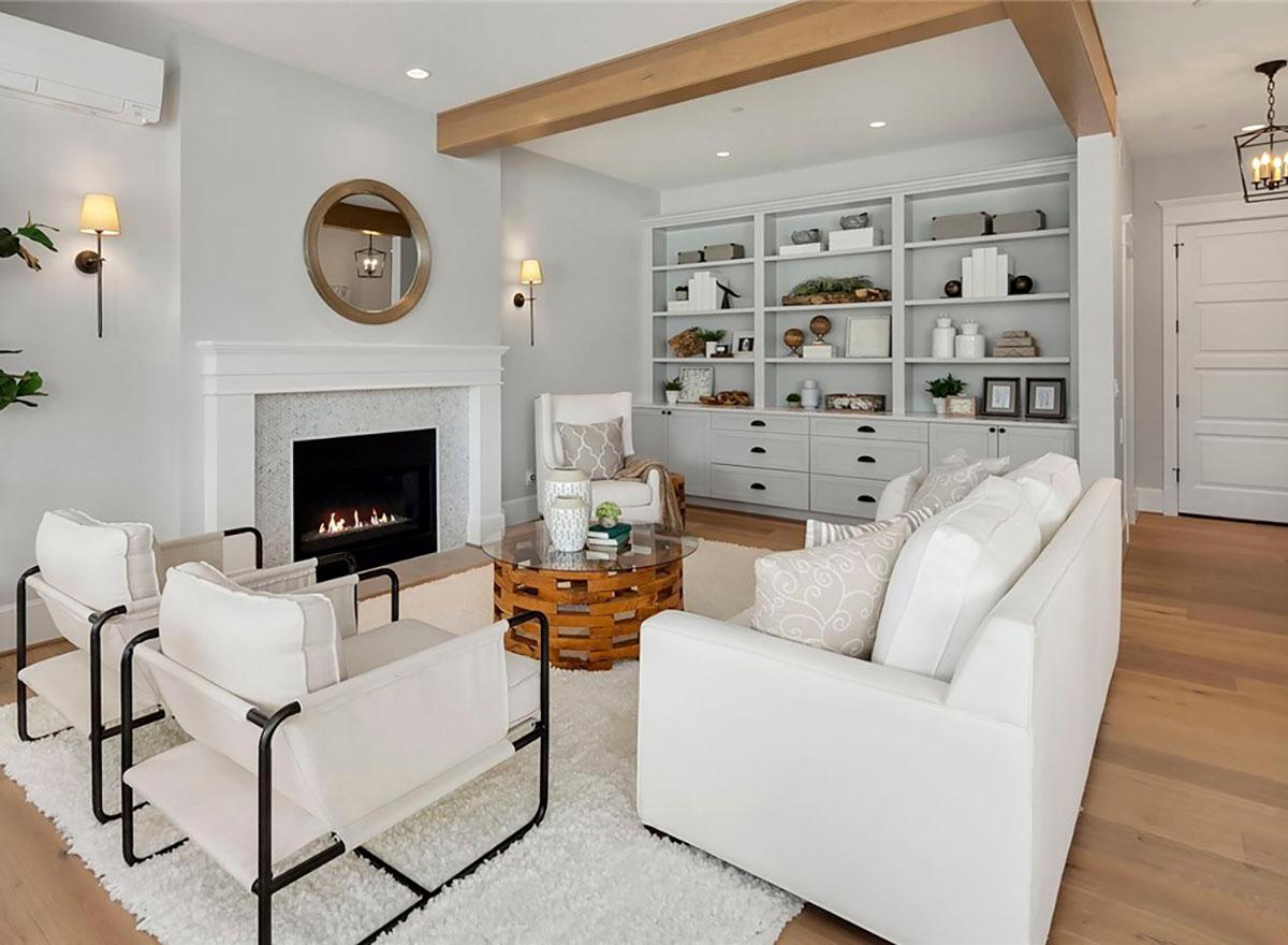 Living room with fireplace, built-in shelving, and wood beam ceiling.