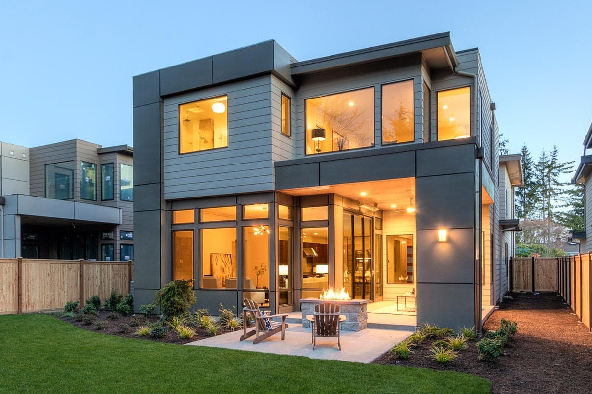 Modern two-story house plan exterior with flat rooflines, extensive glazing, and a covered patio with a fire pit.