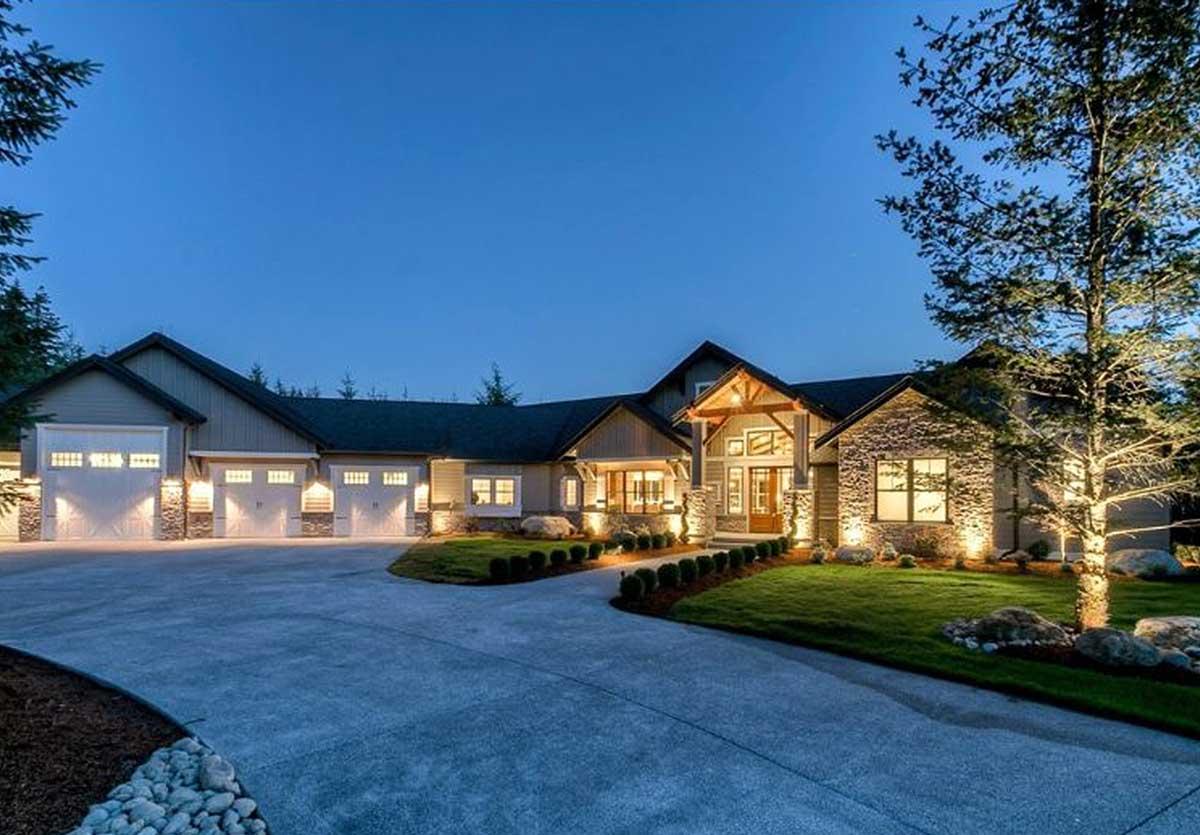 House plan exterior: Ranch style, single-story with a four-car garage, prominent entrance with stone accents, and exposed wood beams.