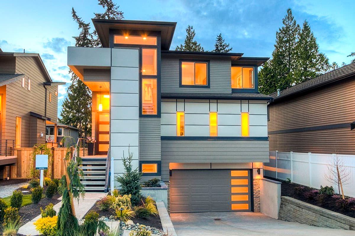Modern house plan exterior. Two-story with flat roof, vertical windows, and attached garage. Entry has a staircase leading to the front door.
