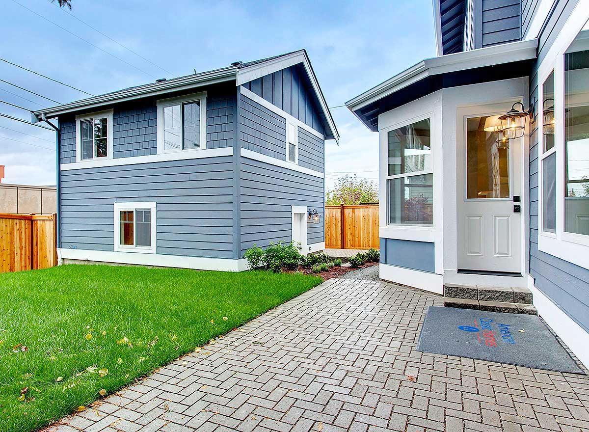 Exterior house plan with blue siding, white trim, gabled roof, and bay window entrance.