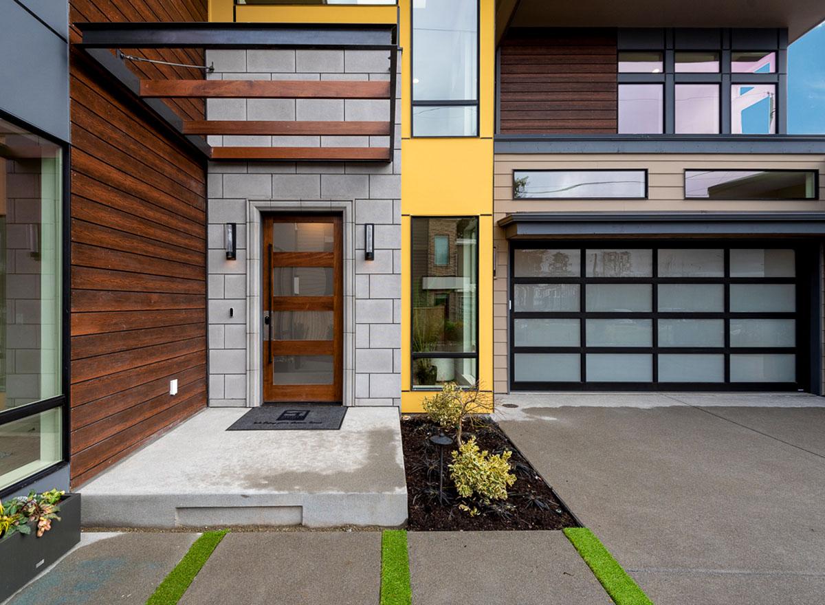 Modern house plan exterior with wood siding, glass entry door, and segmented glass garage door.
