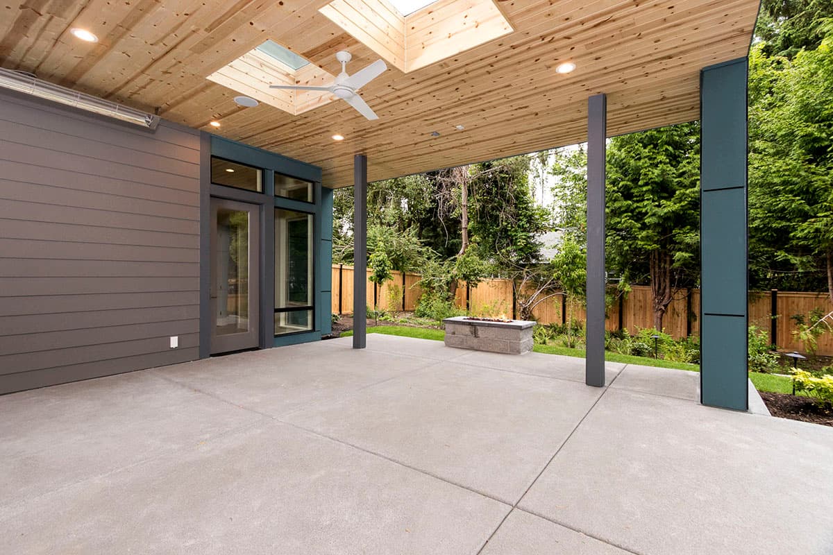 Covered patio with wood plank ceiling, skylights, fan, and built-in fire pit.
