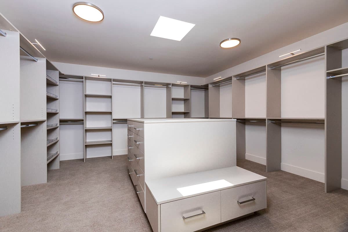 Spacious walk-in closet with a center island, shelving, hanging rods, and drawers.