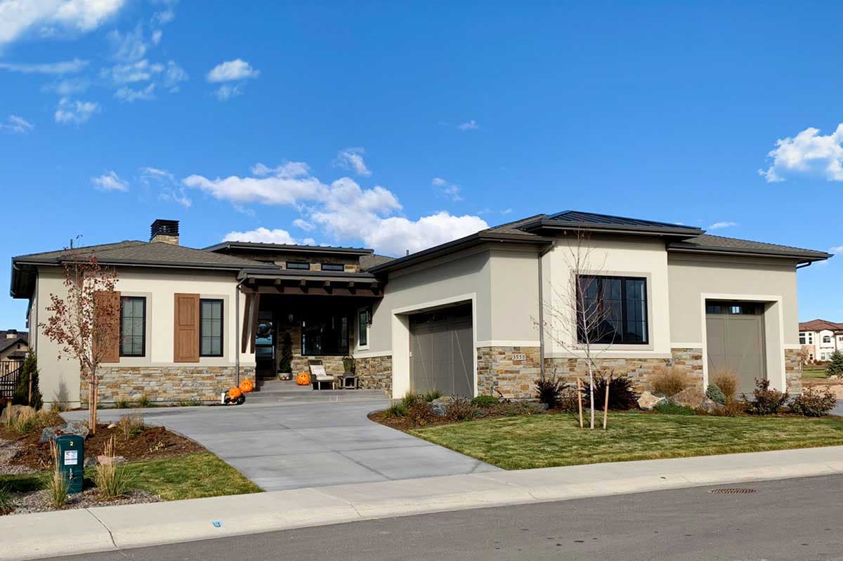 House plan exterior. Modern style, one story, with covered porch, stone facade accents, and attached garage. Includes a driveway.