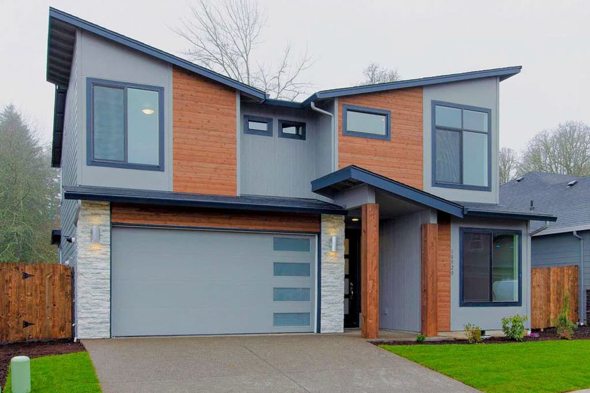 Modern two-story house plan exterior with asymmetrical gables, wood paneling, stone accents, and a segmented garage door.