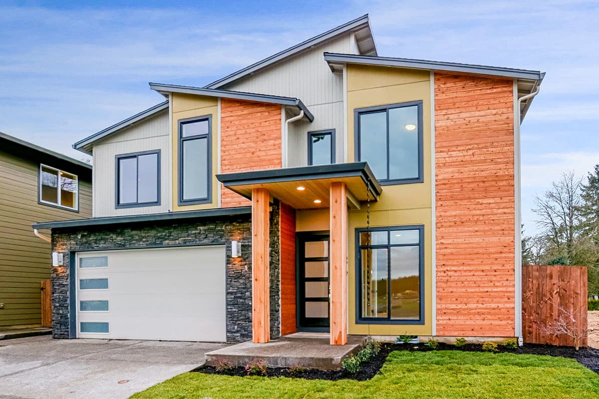 House plan exterior. Two-story Modern house with a low-slope roof, wood siding accents, large windows, and an attached garage with stone detailing.