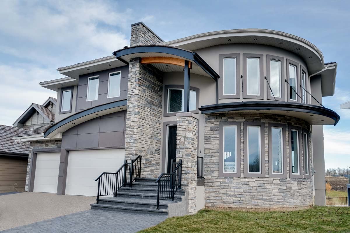 Two-story modern house plan exterior with stone accents, curved bay window, covered entryway, and attached two-car garage.