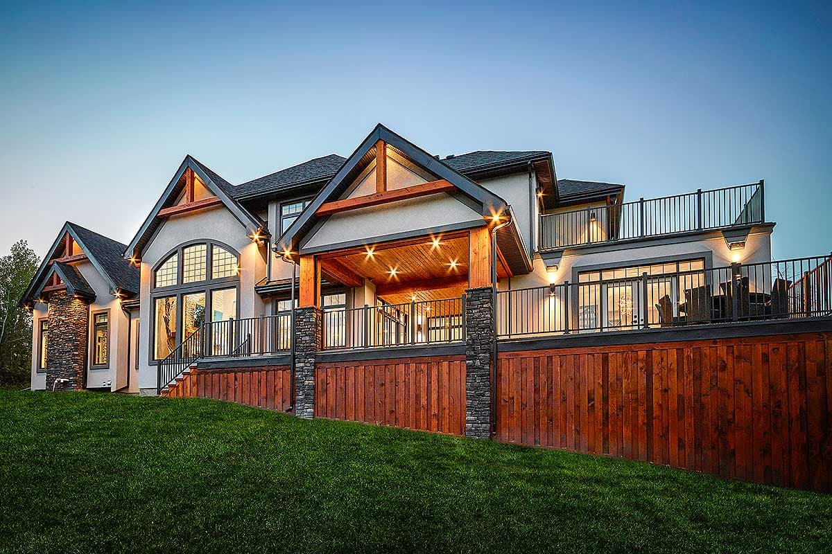 House plan exterior featuring multiple gables, a covered patio with exposed beams, stone accents, and a multi-level deck.