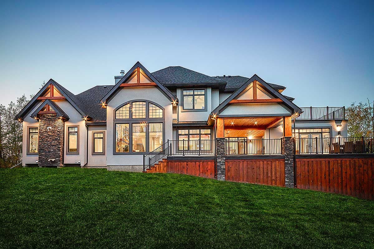 House plan exterior: Two-story Modern Farmhouse with stone chimney, large arched window, and covered deck.