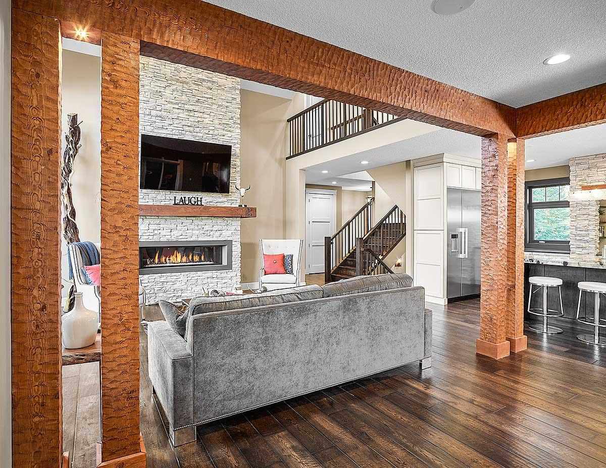Interior rendering of a living area with a stone fireplace, television, bar seating, and a staircase leading to an upper level.
