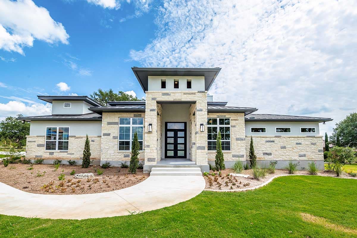 House plan exterior. Modern style, one-story home with flat roof, stone facade, and a central entry with a recessed porch.