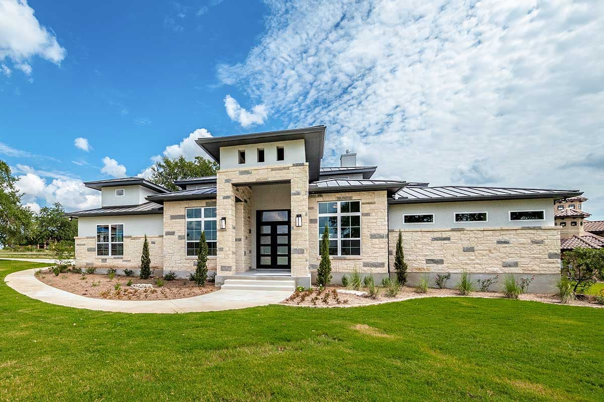 Modern ranch house plan exterior with stone accents, metal roof, and prominent entryway with glass door.
