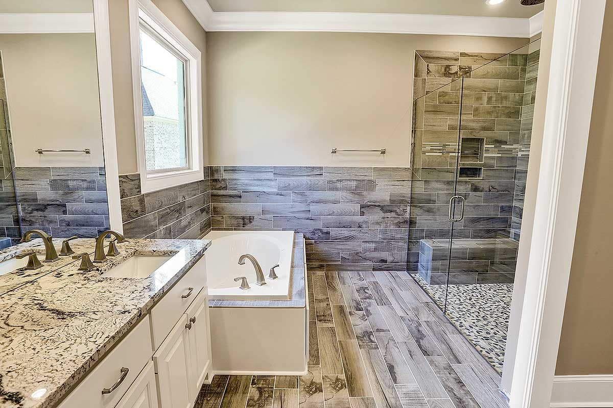 Bathroom with double vanity, soaking tub, and glass-enclosed shower with tiled walls and stone floor.