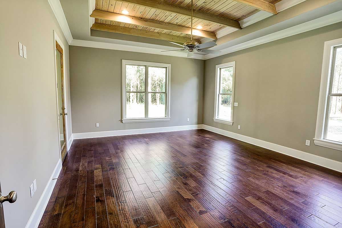 Interior view of a room featuring a coffered wood ceiling, hardwood floors, and three windows.