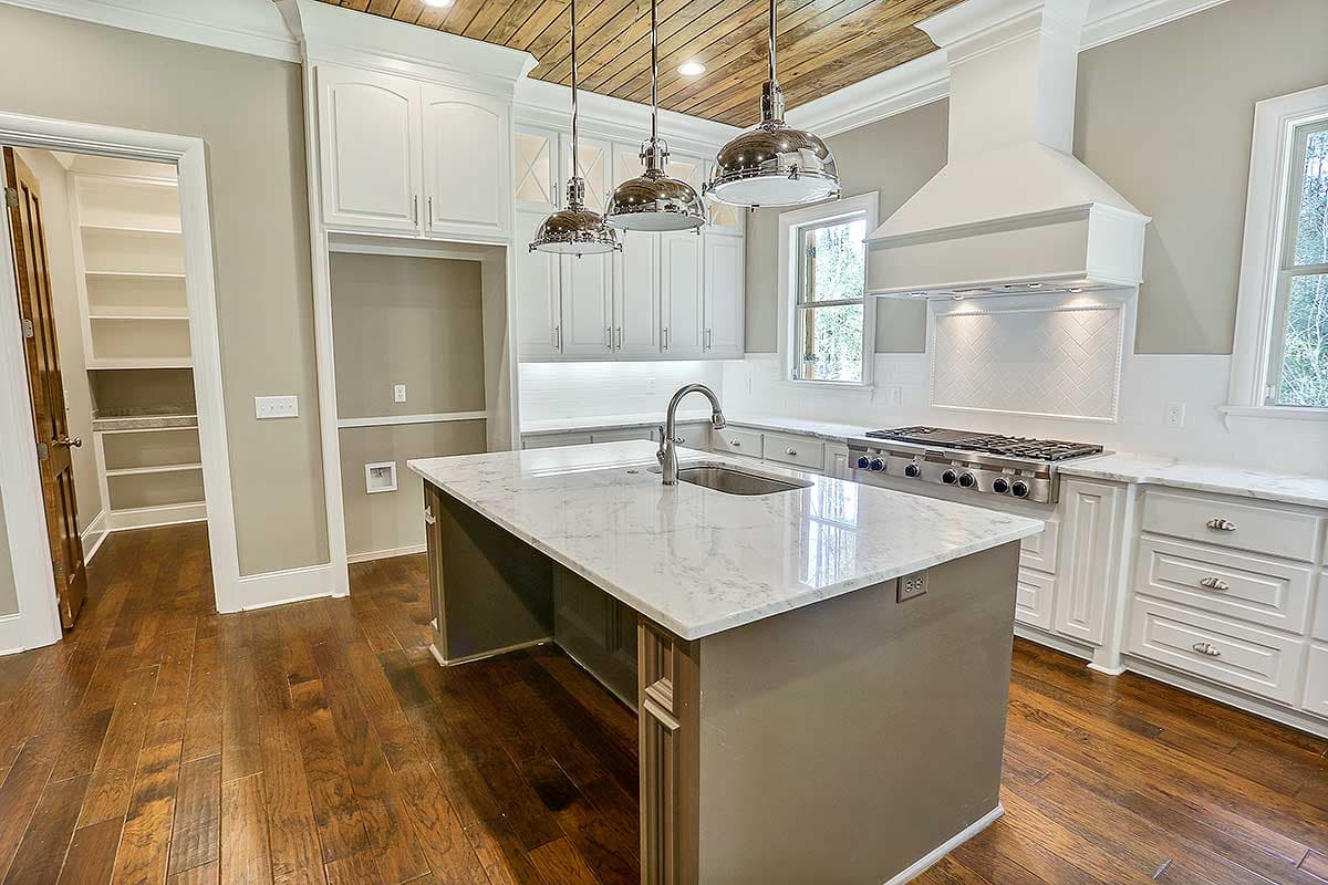 Kitchen with large island, stainless steel appliances, white cabinetry, and wood plank ceiling.