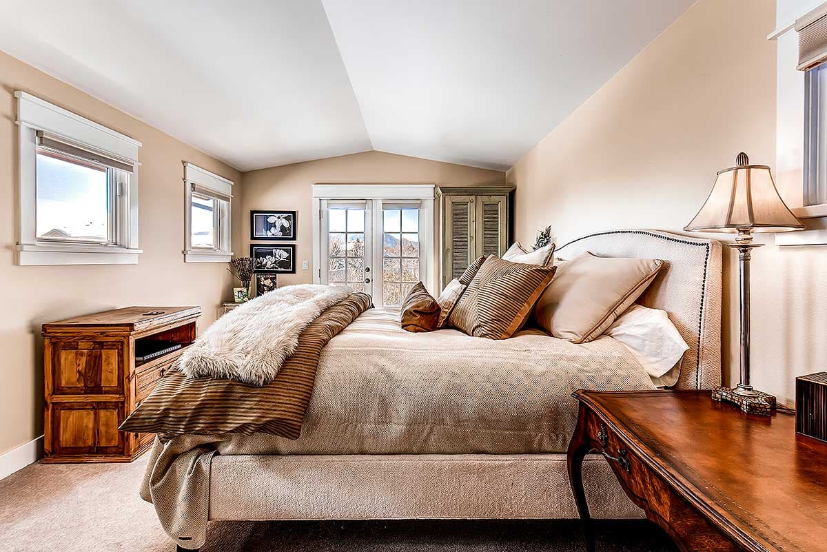 Bedroom with vaulted ceiling, French doors to outdoors, and two windows.