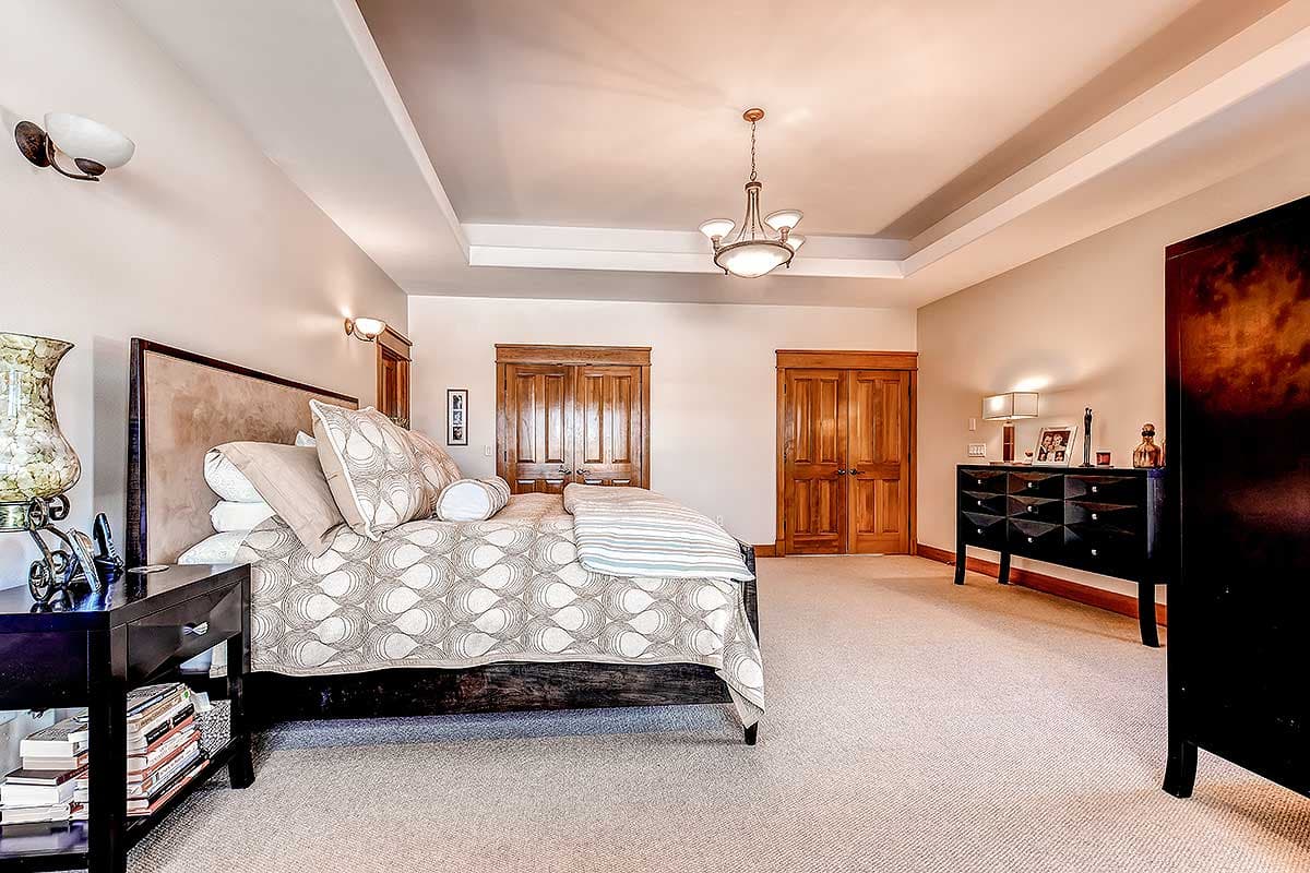 Bedroom interior with double closet doors, tray ceiling, and light fixtures.