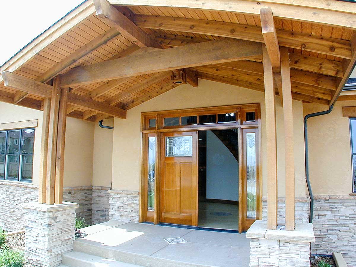 House plan exterior featuring a covered porch with exposed timber beams, stone veneer base, and double wood entry doors.