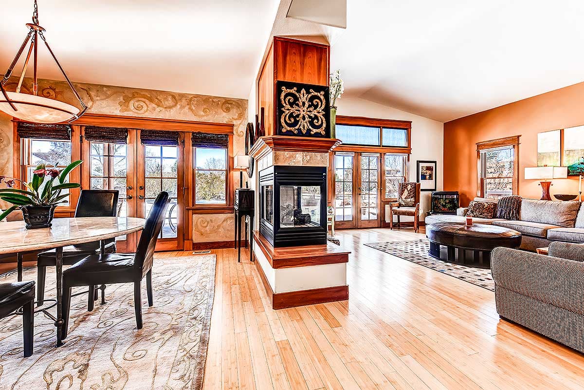 Interior rendering of a great room with a fireplace, dining area, and living room with vaulted ceilings.