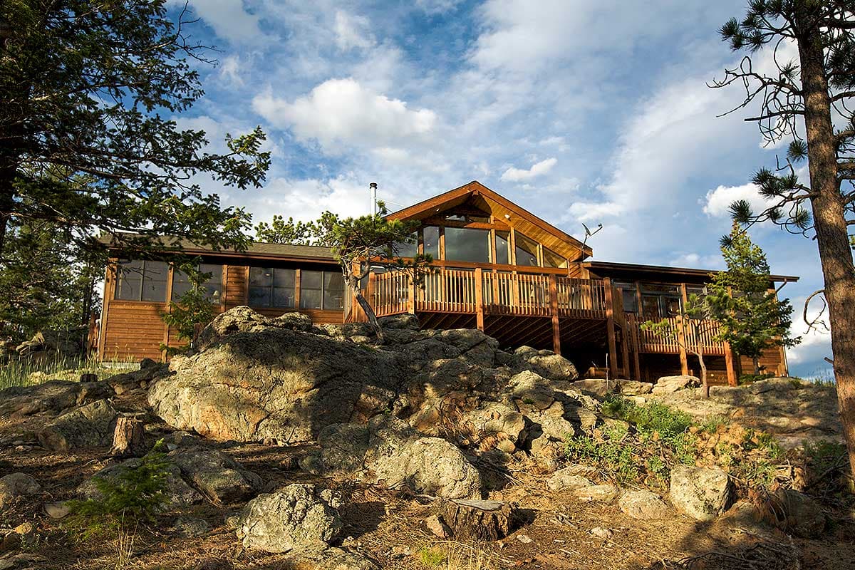 Modern wooden house plan exterior with large deck, prominent gables, and extensive windows.