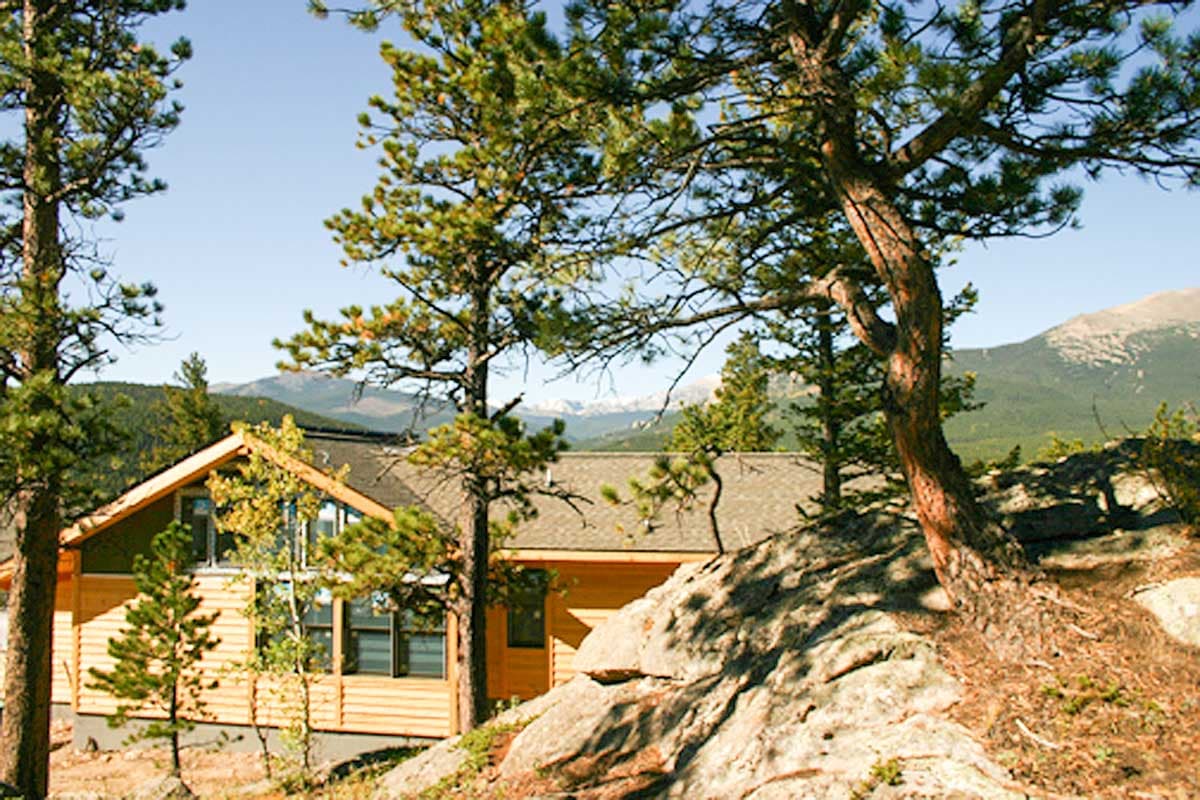 House plan exterior: Modern lodge-style, wood siding, prominent gables, and large windows facing mountains.