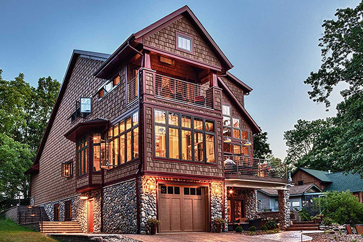 House plan exterior: Three-story home with stone base, cedar shingles, prominent gables, multiple balconies, and large windows.