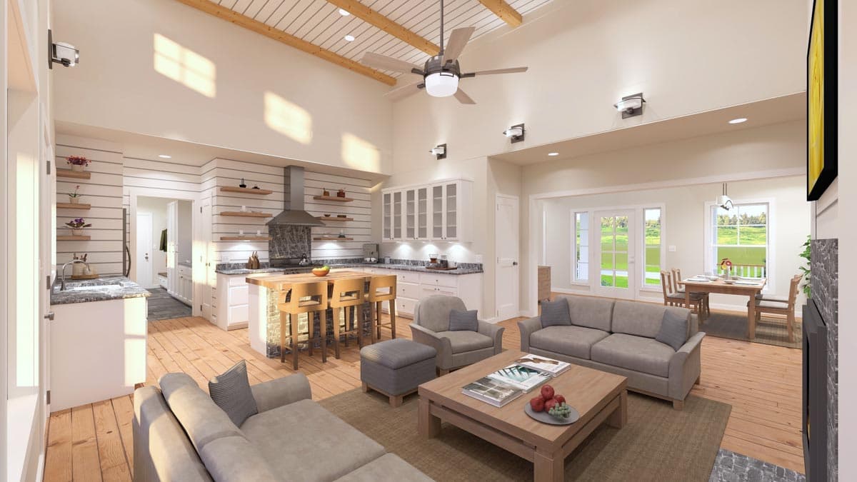 Spacious, open-plan living and kitchen area with light wooden floors, white cabinets, and comfortable seating. Includes dining area and a fan.