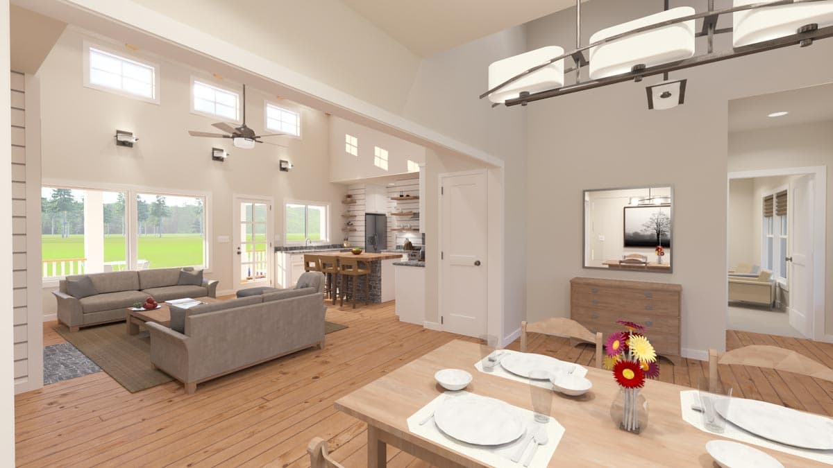 Spacious, open-concept interior with a living area, dining table, and a kitchen visible in the background, flooded with natural light.