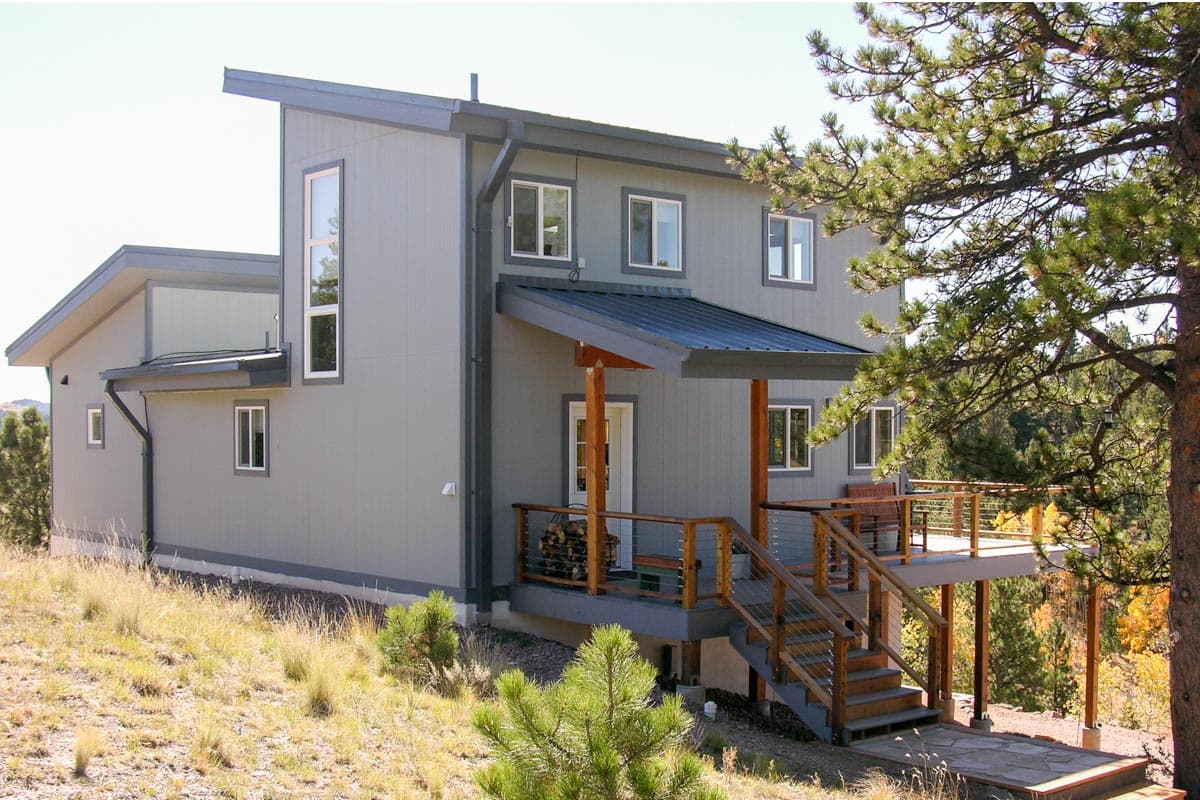 House plan exterior: Modern two-story home with asymmetric rooflines, covered entry porch, and wraparound deck.