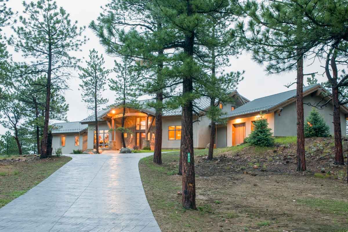 House plan exterior: Modern style with stone accents, prominent wooden beams on the covered entry, and multiple gables.