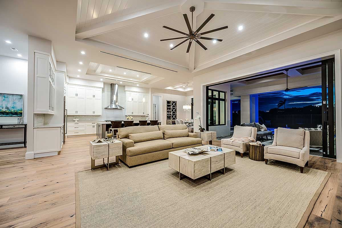 Open concept living area with kitchen, great room, vaulted ceiling, large fan, and lanai access.