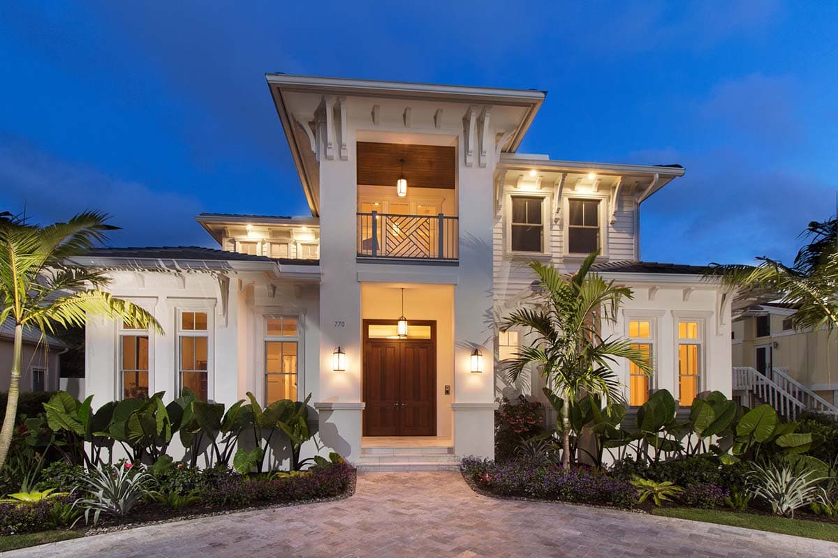 House plan exterior. Two-story, coastal-style home with a balcony, prominent entry, and a multi-gabled roofline.