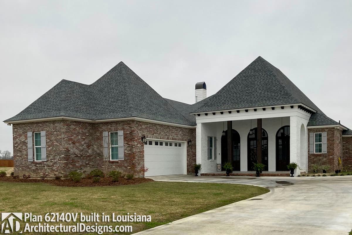 House plan exterior with brick and white stucco, prominent gabled rooflines, attached garage, and arched entry portico.