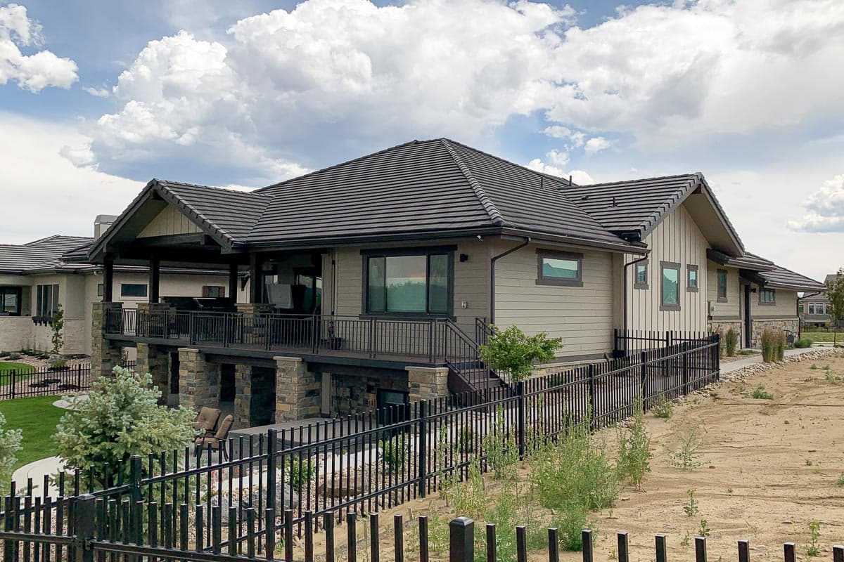 House plan exterior: Modern ranch with covered deck, stone accents, gabled rooflines, and neutral siding.