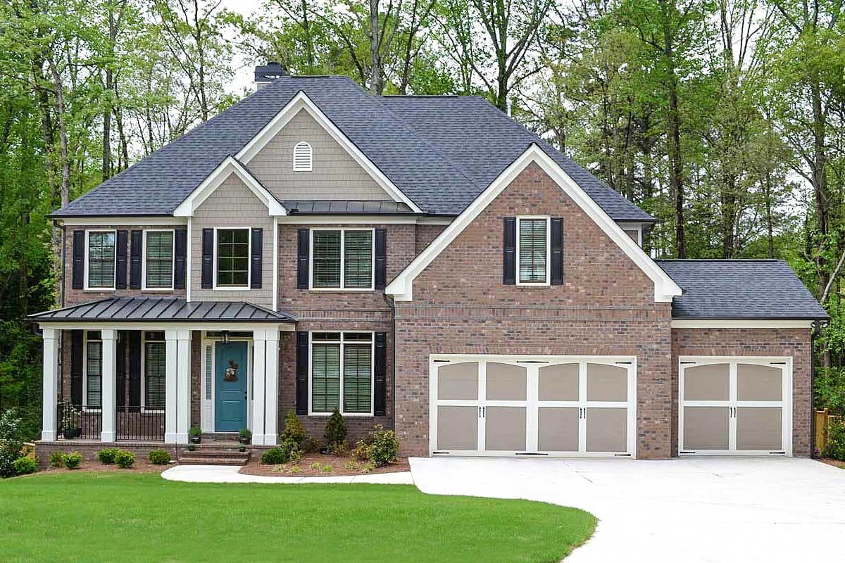 House plan exterior. Two-story brick home with gabled roof, front porch, and attached garage. Includes decorative shutters and dormers.
