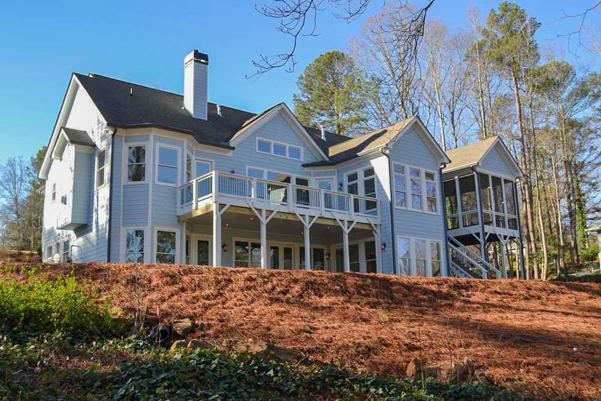 House plan exterior showing a two-story light blue siding home with a large deck, multiple gables, and a screened porch.