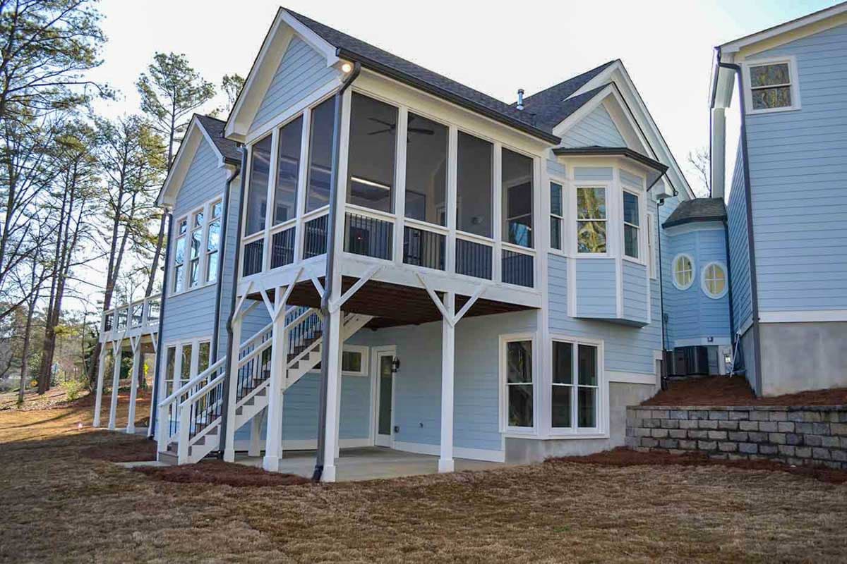 House plan exterior: Two-story light blue home with a raised screened porch, white railings, bay window, and a multi-story design.