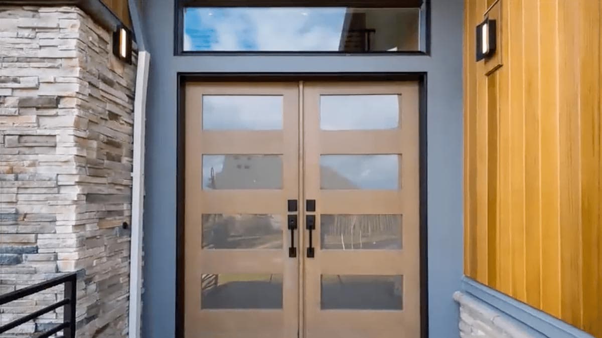 Modern house exterior with double wood doors, stone accent wall, and wood siding.