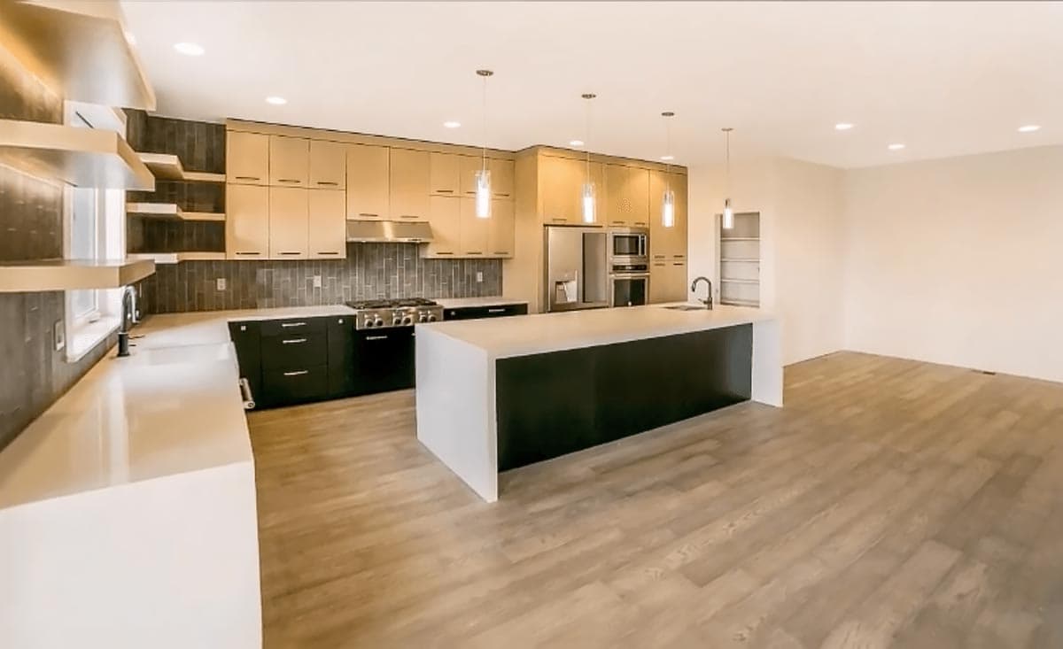 Modern kitchen with large island, sleek cabinetry, stainless steel appliances, and ample counter space.