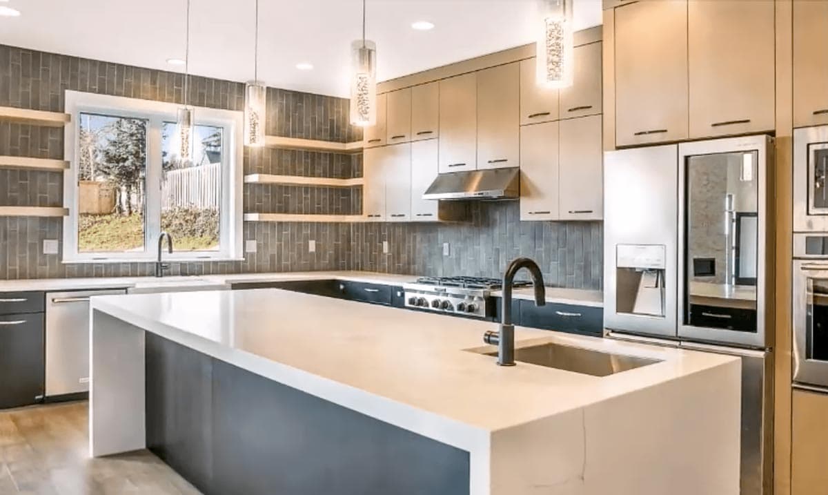 Modern kitchen with large island, stainless steel appliances, sleek cabinetry, and subway tile backsplash.