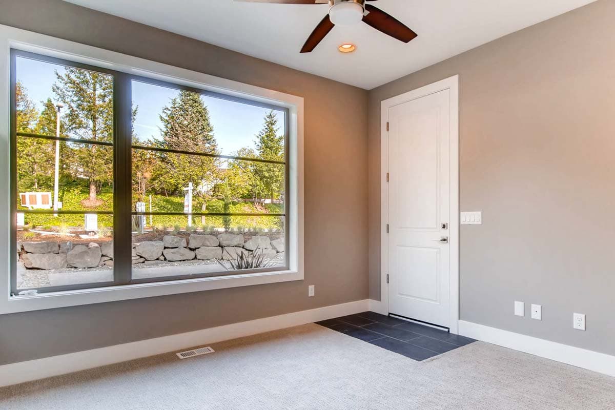 Interior view of a room with a large grid window, ceiling fan, and white paneled door.