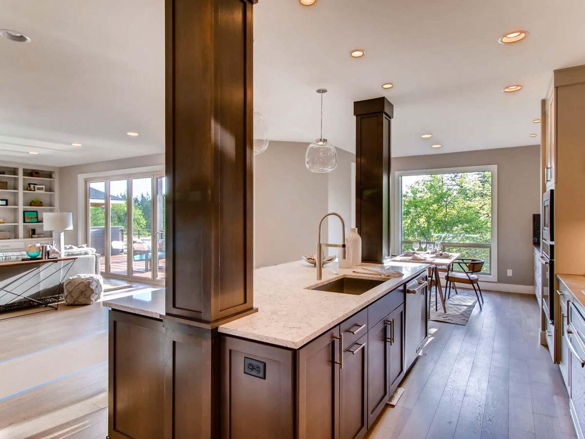 Open concept living area with kitchen island featuring stainless steel sink and dark wood cabinetry, connected to dining and living spaces.
