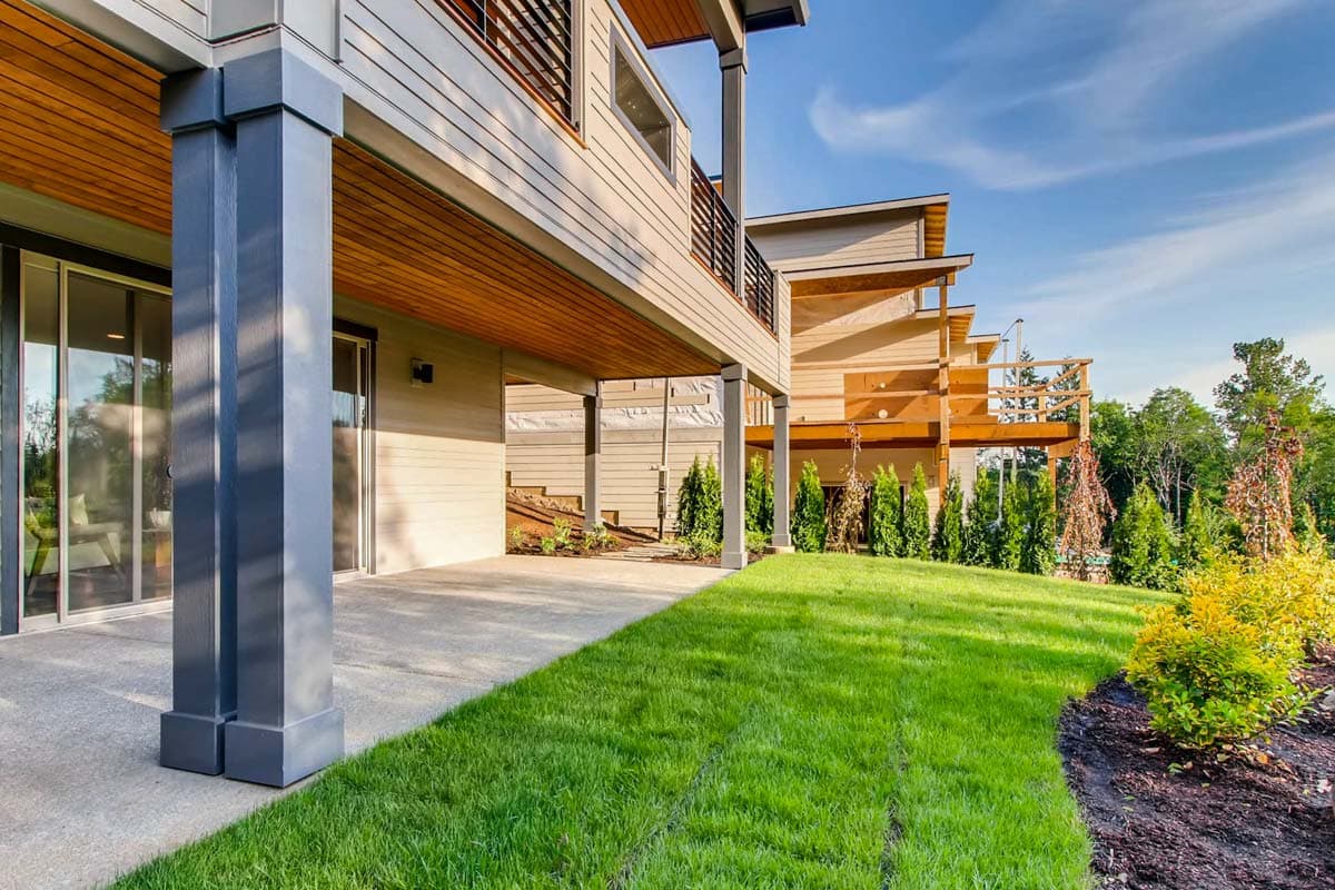 Modern house plan exterior with multiple levels, wood soffits, large support columns, and balconies.