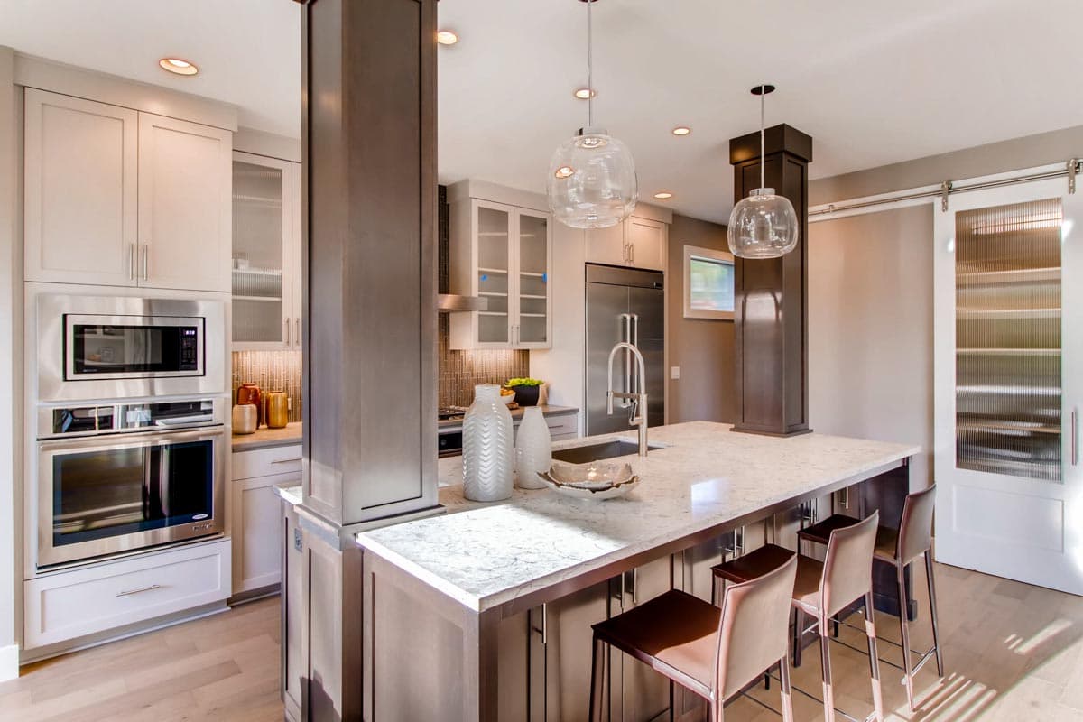 Kitchen with island, stainless steel appliances, pendant lights, and a sliding barn door with frosted glass.