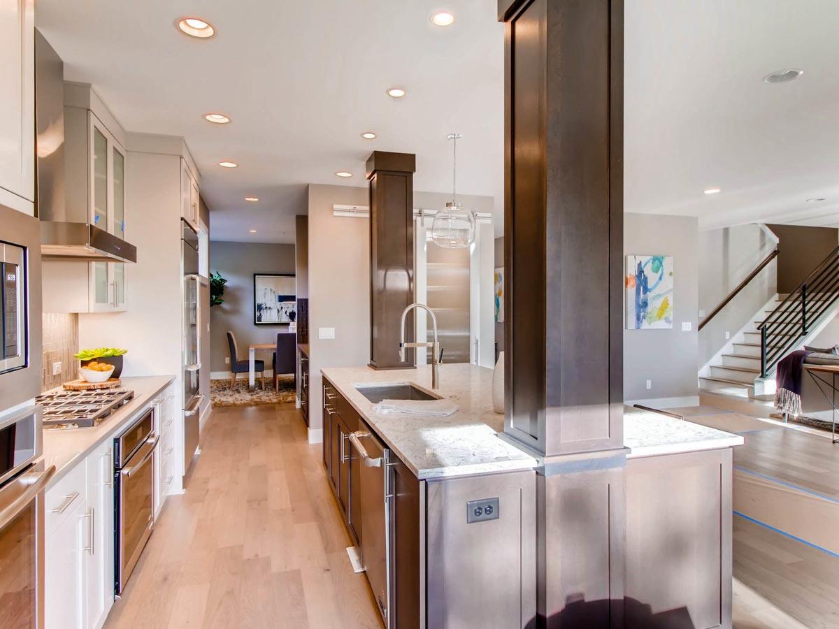 Contemporary kitchen with island, stainless steel appliances, and open stairway leading to upper level.