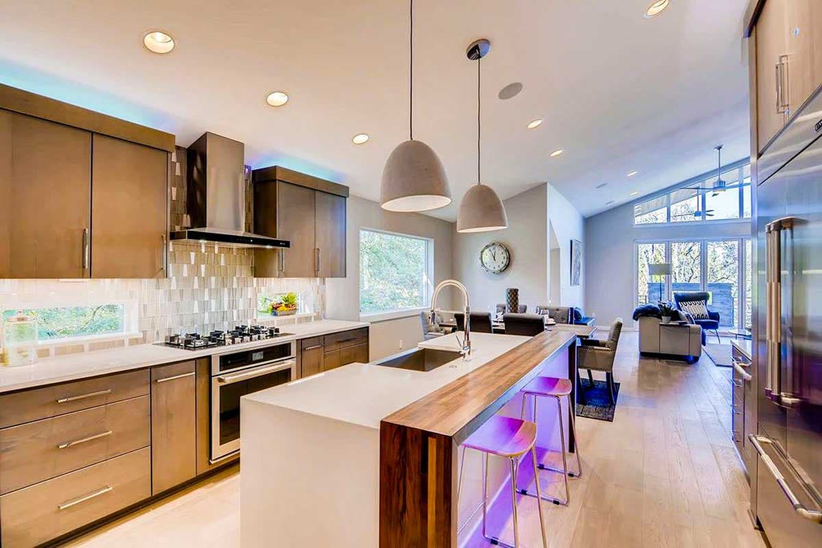 Modern open-concept kitchen with a large island, stainless steel appliances, and a dining area beyond.