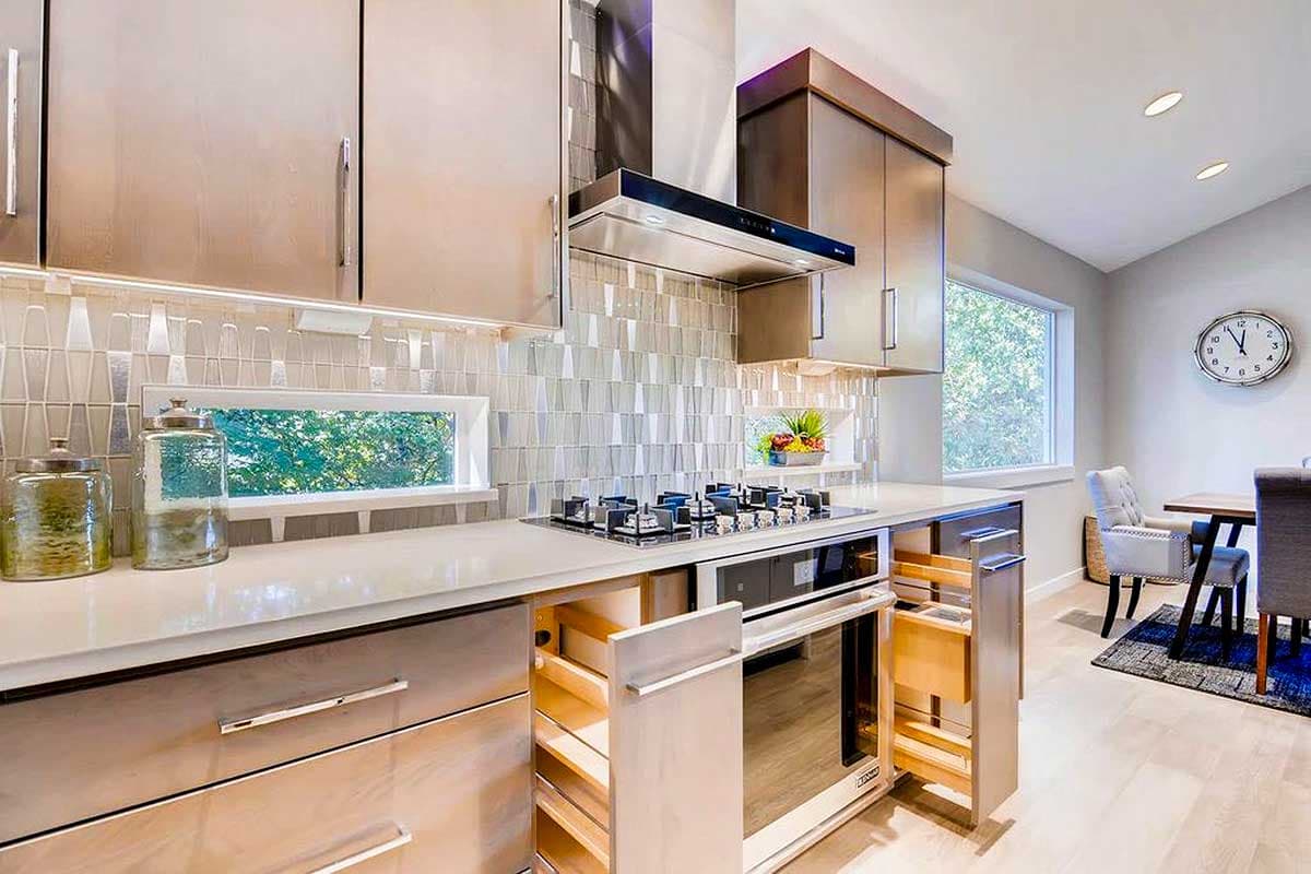 Modern kitchen with stainless steel appliances, gas range, custom backsplash, and pull-out drawers.